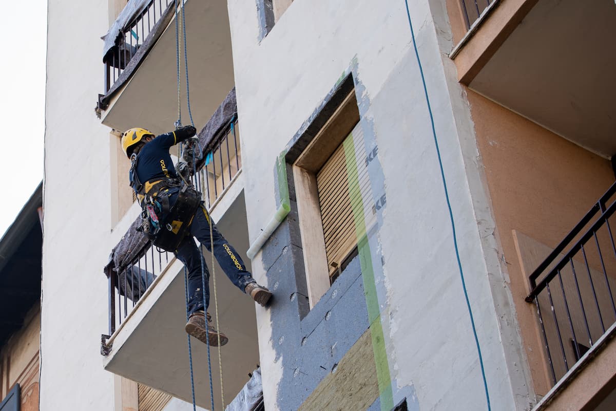 una delle fasi di realizzazione del cappotto termico. Operaio Acrobatica su fune.