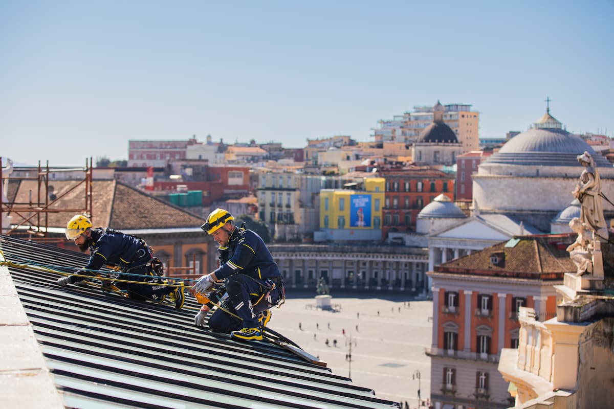 Foto con esempi di tetti diversi a Napoli e sulla destra due operai Acrobatica durante un intervento su uno di essi