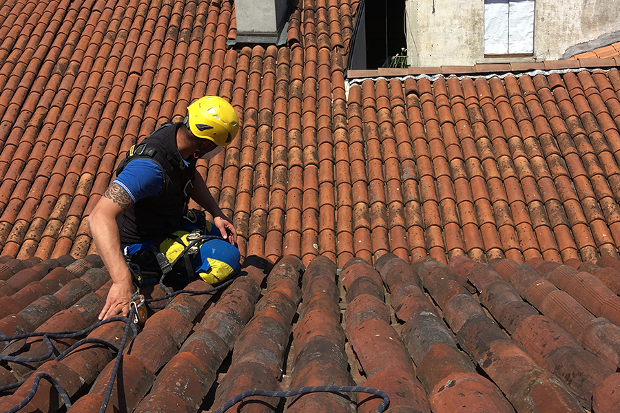 Linee vita provvisorie: operaio Acrobatica su tetto di spalle appeso a fune