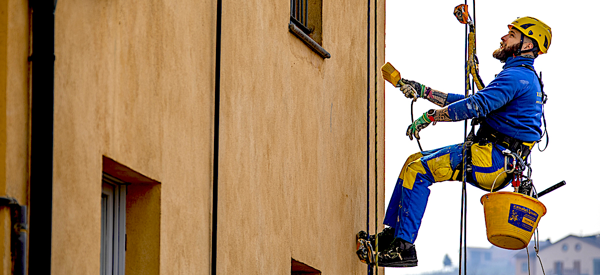 Operatore edile in tuta Ediliziacrobatica che osserva la facciata di un edificio a Barolo