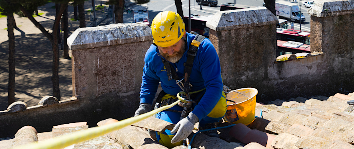 Lavoratore sopra il tetto che sostituisce le tegole rotte 
