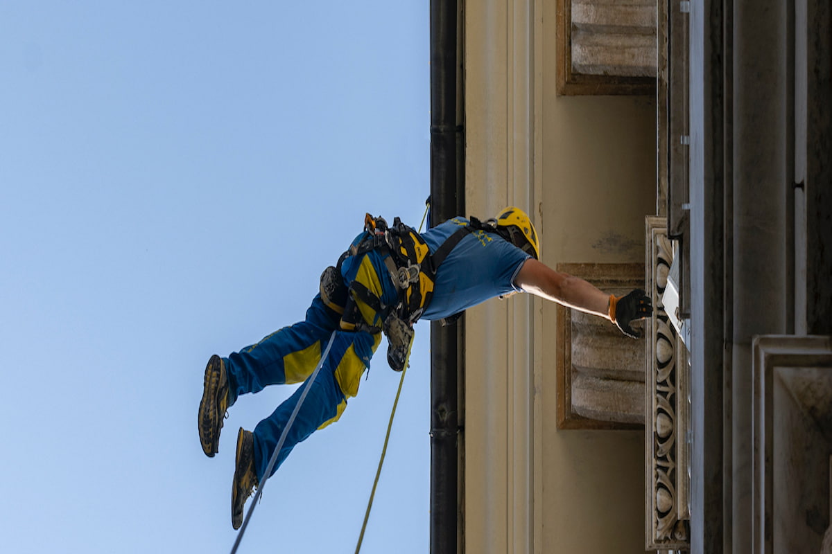 Operaio Acrobatica ripreso dal basso durante una attività di manutenzione del tetto straordinaria