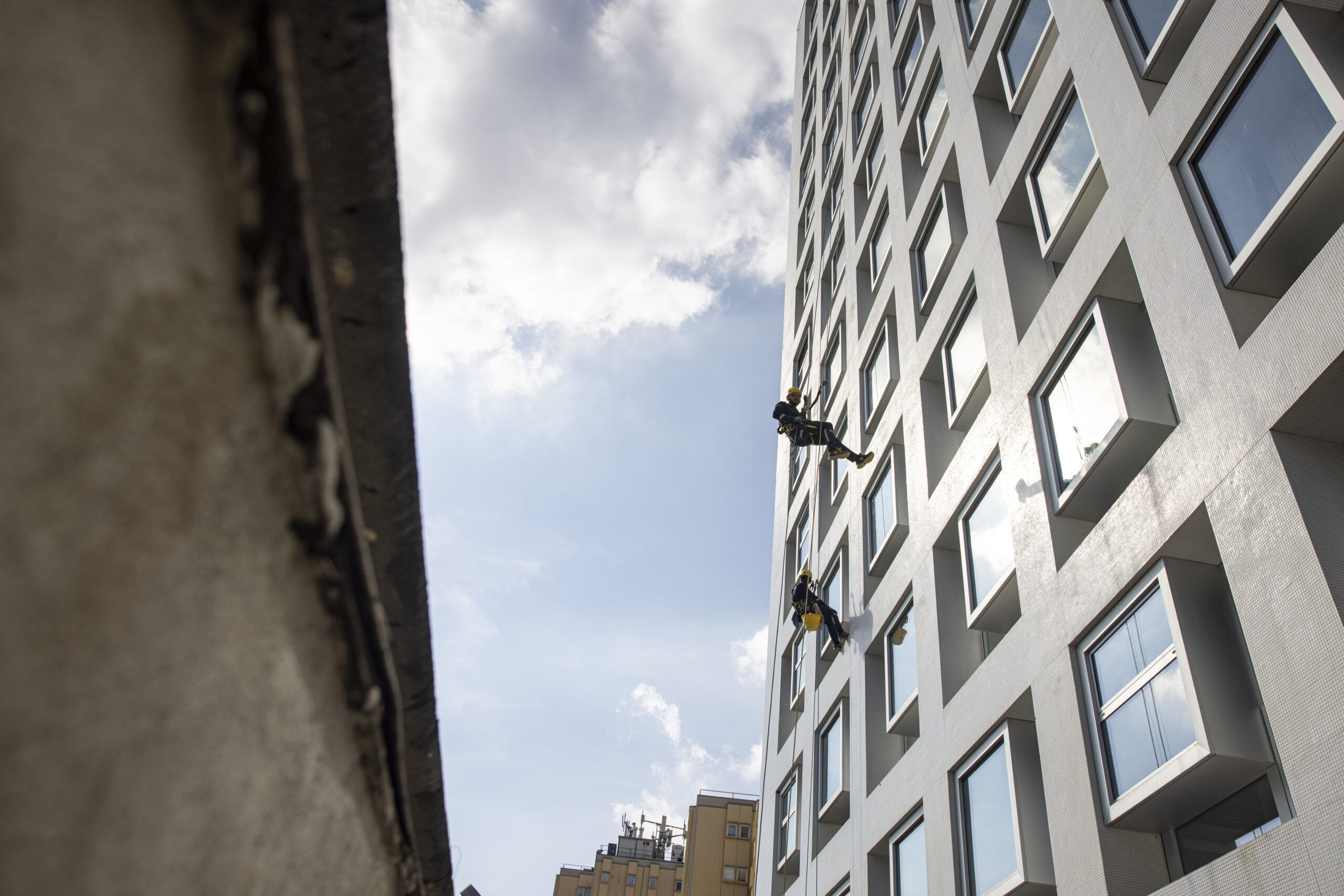 Immagine di un condominio in fase di lavori, operai visibili al lavoro su fune