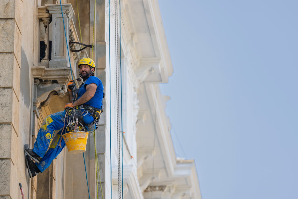 Operaio su fune lavora alla facciata di un edificio a Genova, in riferimento alla scadenza del Bonus Facciate