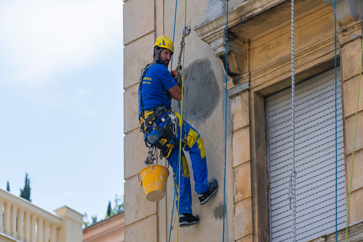 Operaio Acrobatica durante lavoro di rifacimento facciata in quota, su fune