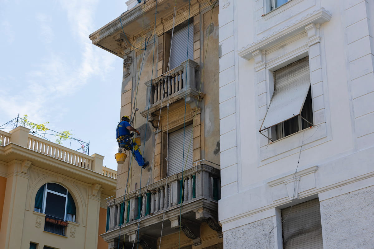 Immagine di un condominio in fase di lavori, operai visibili al lavoro su impalcature, rappresentazione dell'orario dei lavori in condominio