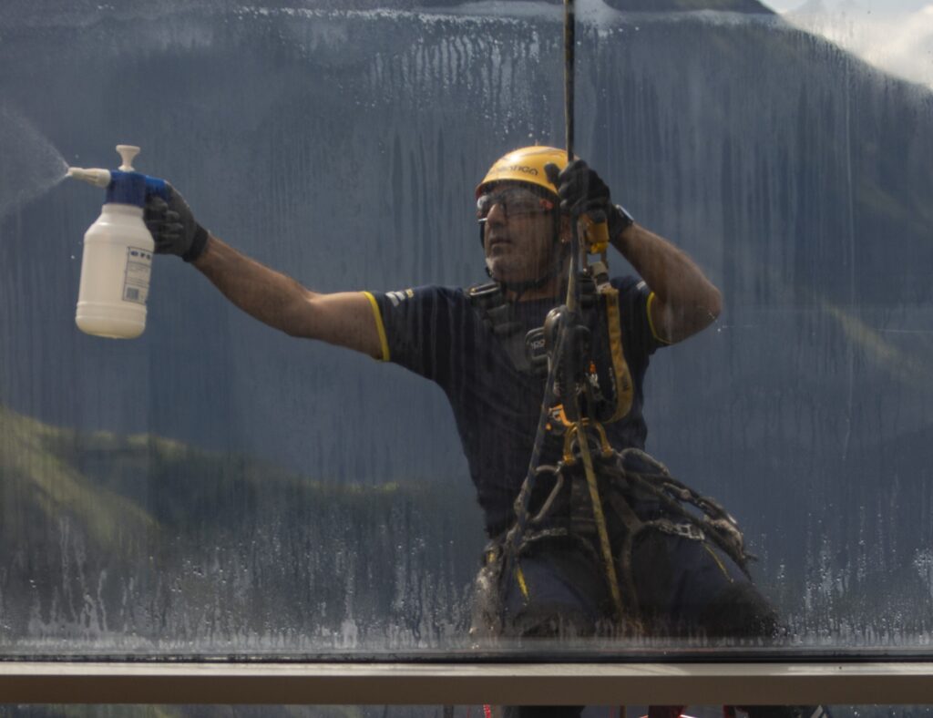 Professionista Acrobatica in azione per pulire vetri esterni molto sporchi
