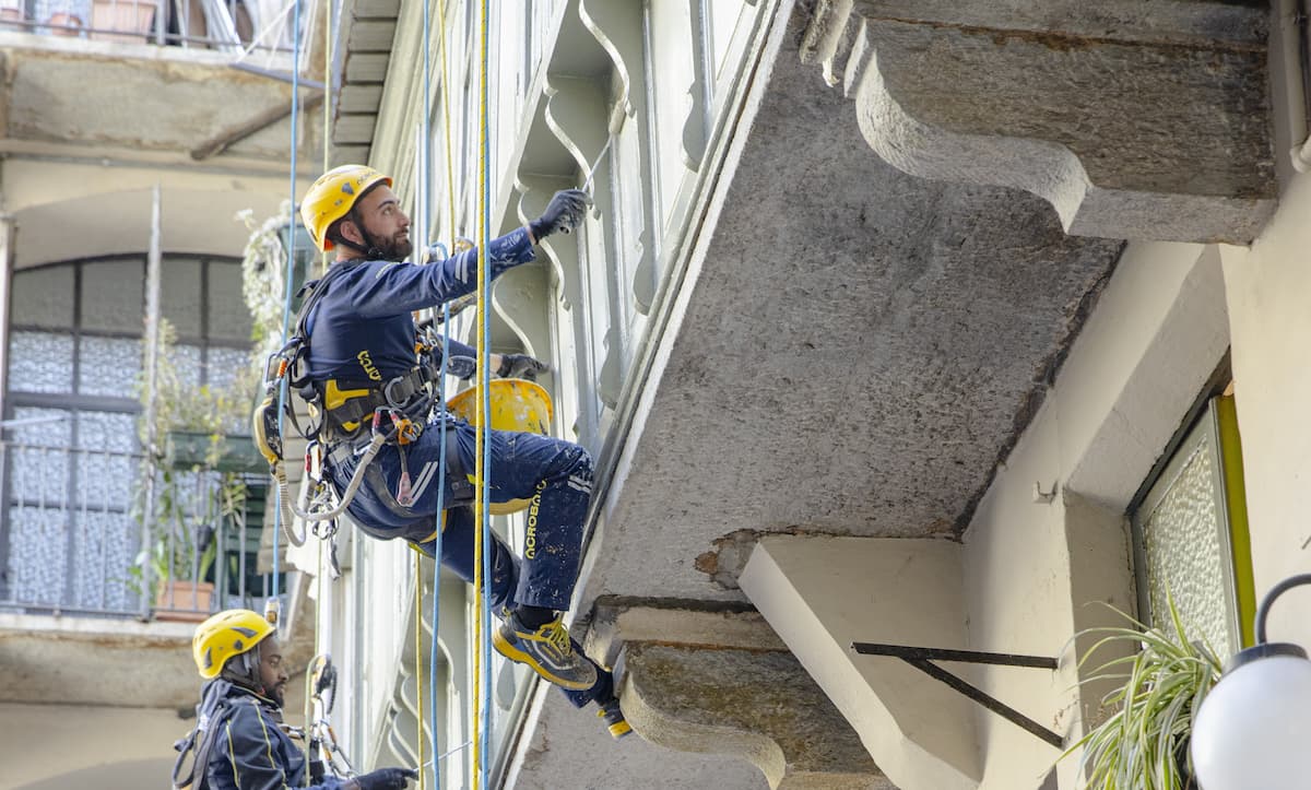 operai Acrobatica su fune durante ritinteggiatura balcone